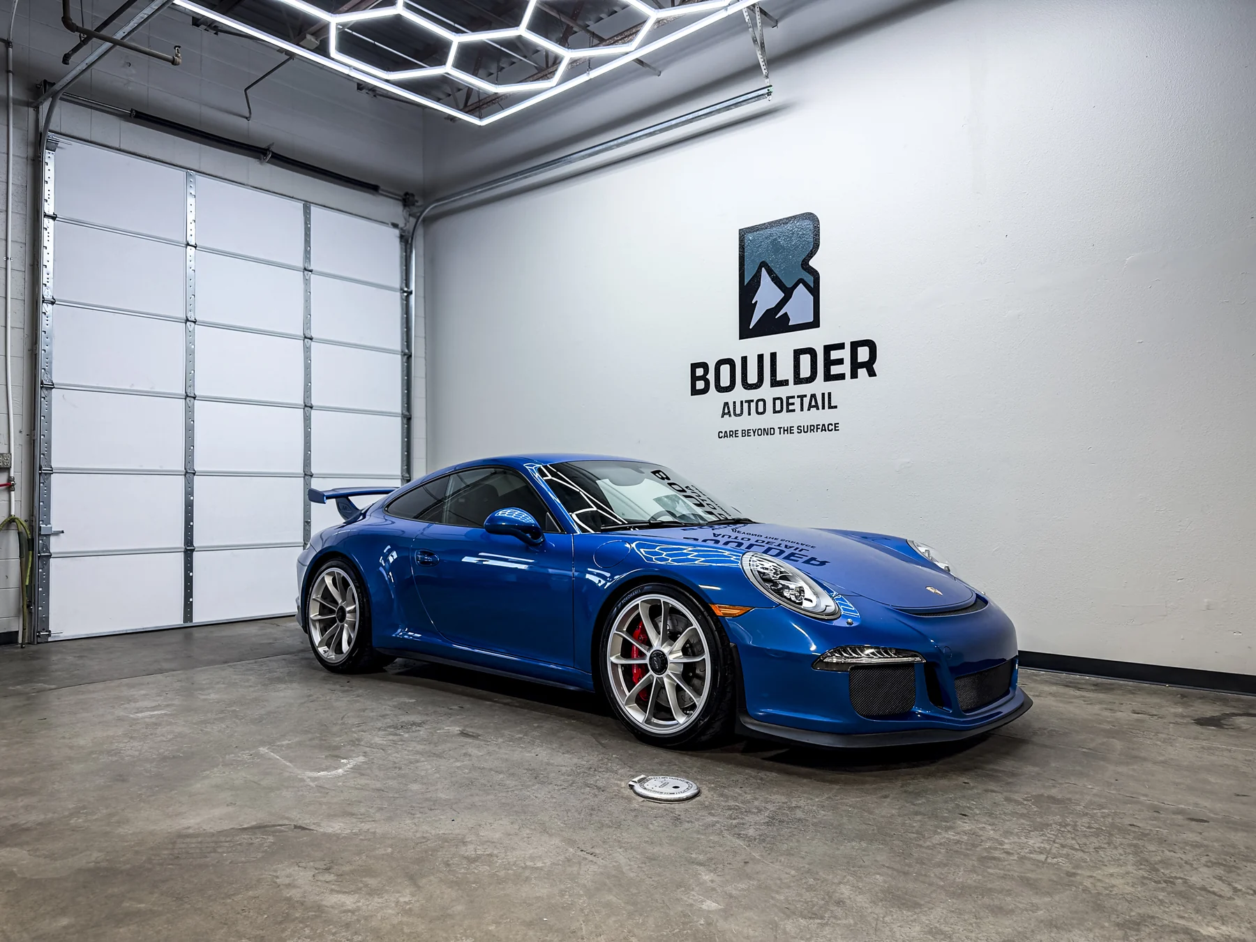 Blue Porsche 911 photographed beneath Boulder Auto Detail shop lighting