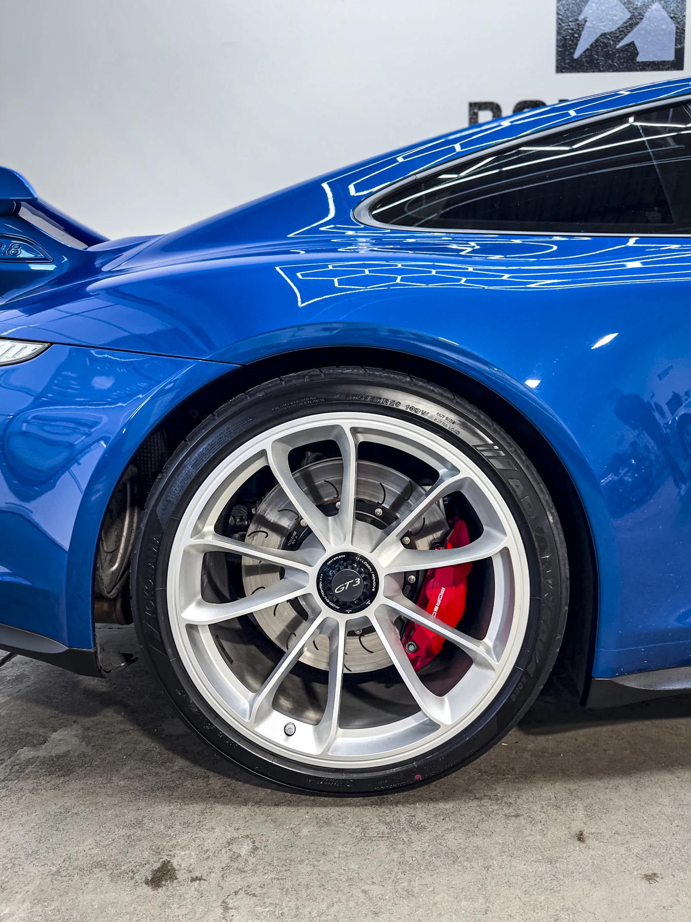 Blue Porsche front wheel and reflective fender detail